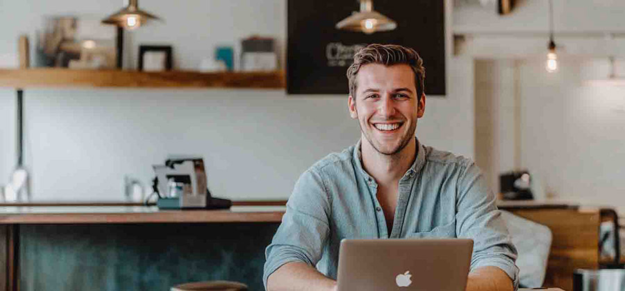 young businessman smiling while working at a coffee shop